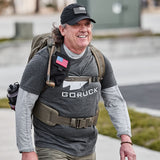 Man rucking outdoors in GORUCK Three Rules Tee, black cap, backpack, and tactical belt