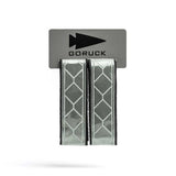 The Reflective Ruck Bands, featuring a geometric pattern for improved nighttime visibility, are sold as two Velcro straps on a GORUCK branded card.